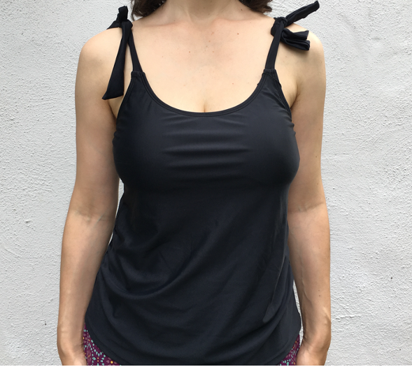 Front view of white woman wearing black tankini top, with straps tied at the shoulders